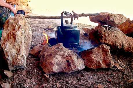 Cooking a tea pot in the fire to make some tea.
